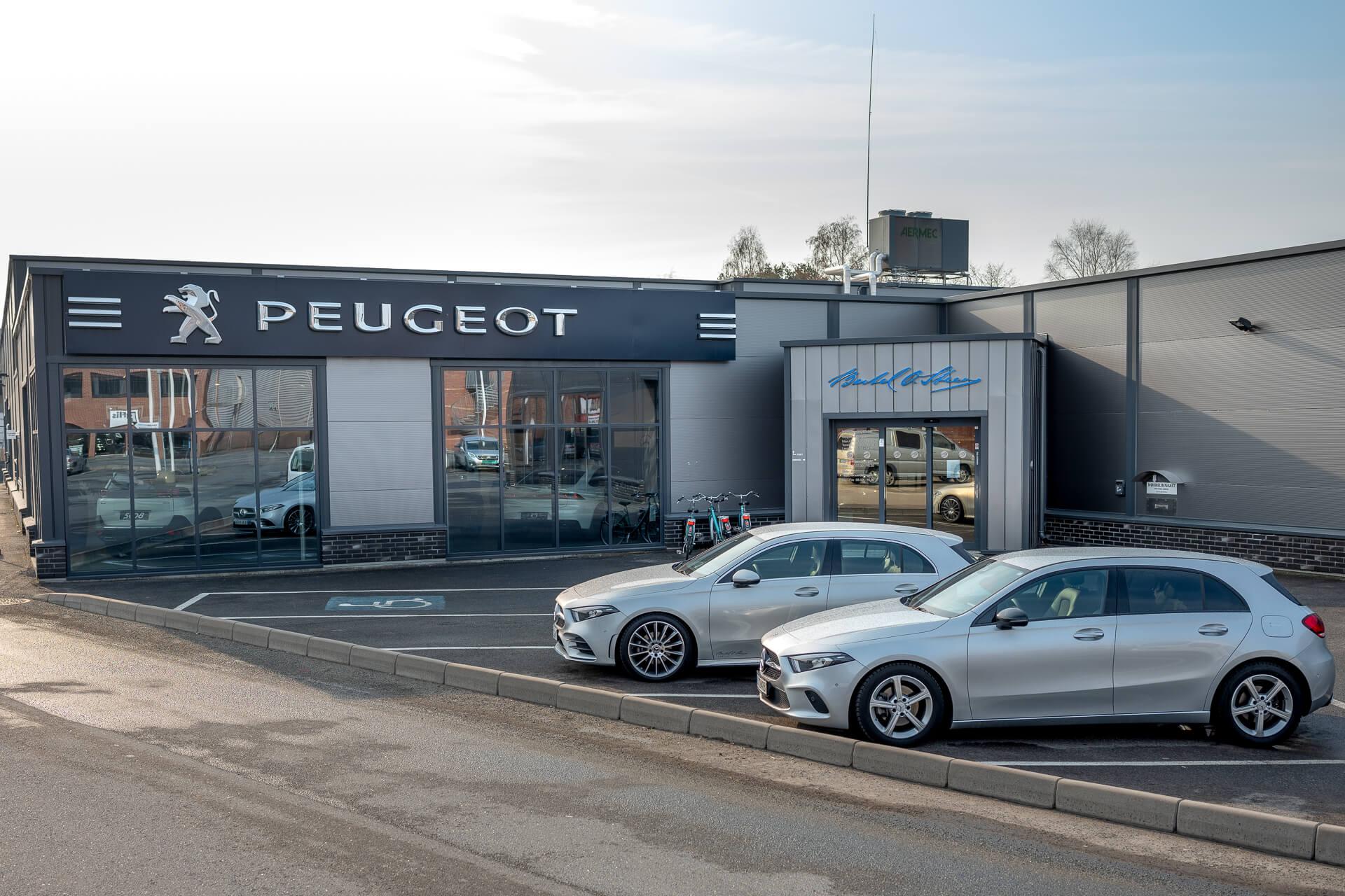 A car showroom with glass front and cars parked outside