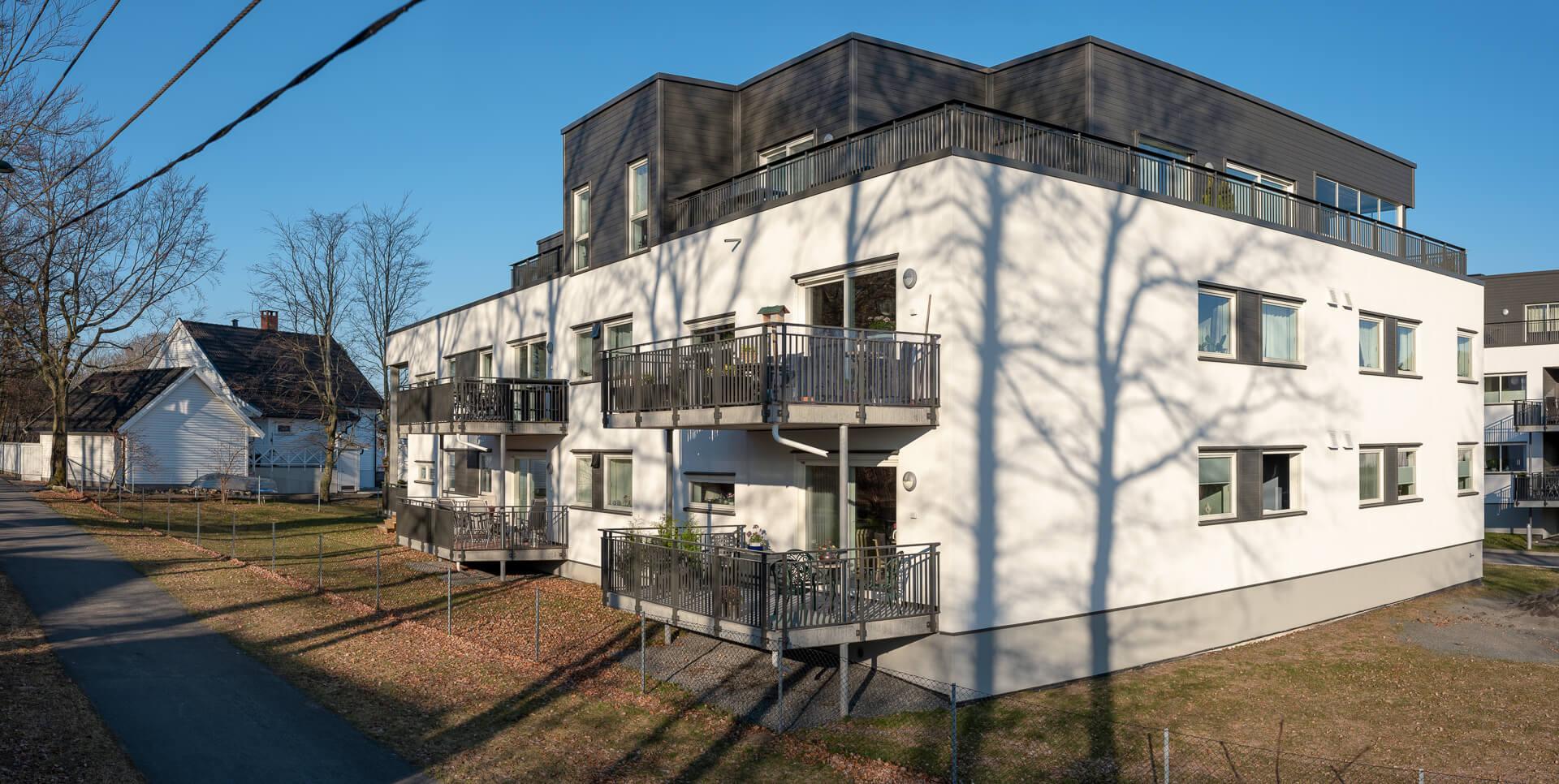 A white three-storey apartment block with dark top floor