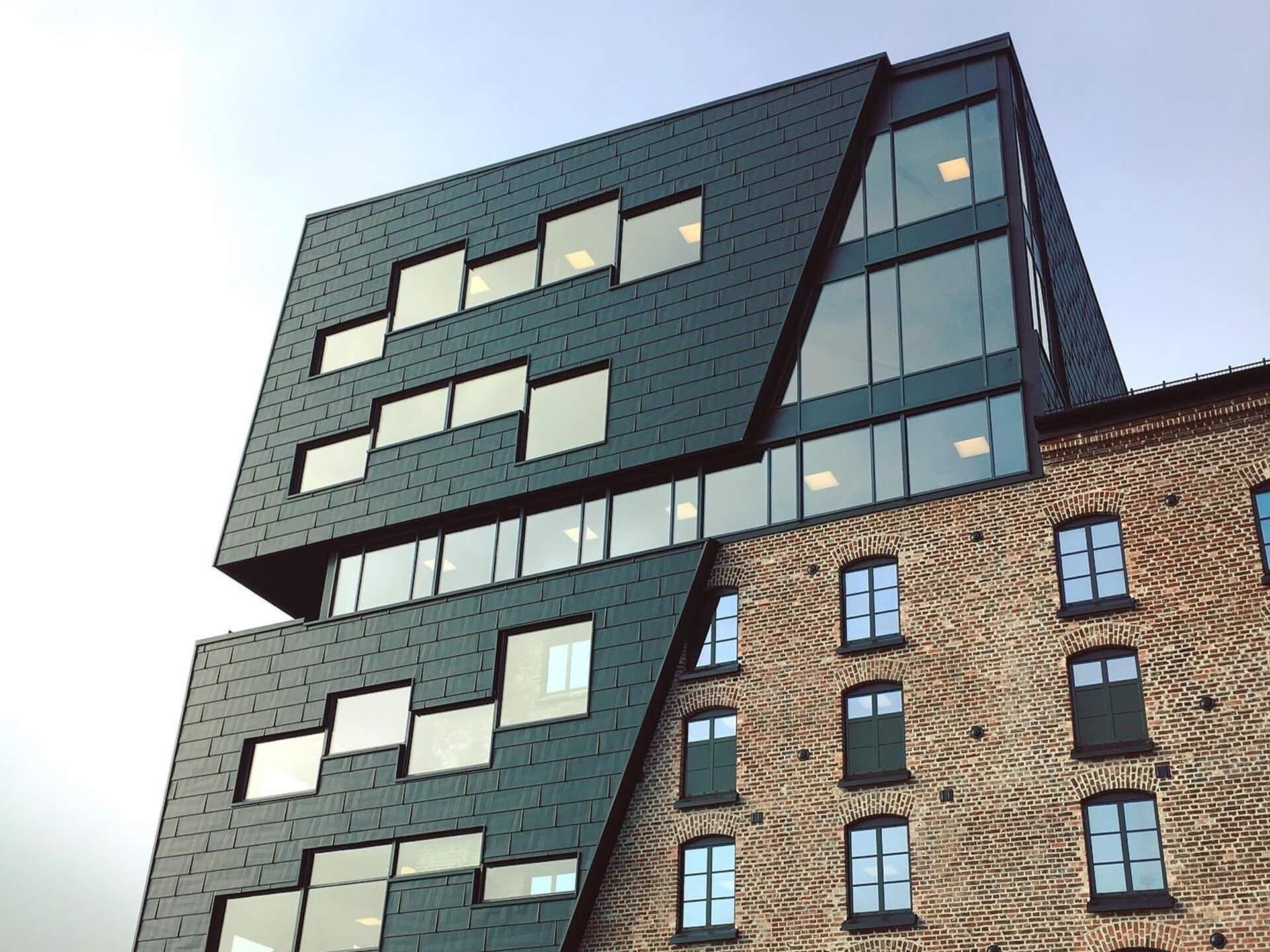 The new Fritzøe Mølle building in Larvik: dark angled cladding with large windows above old brick
