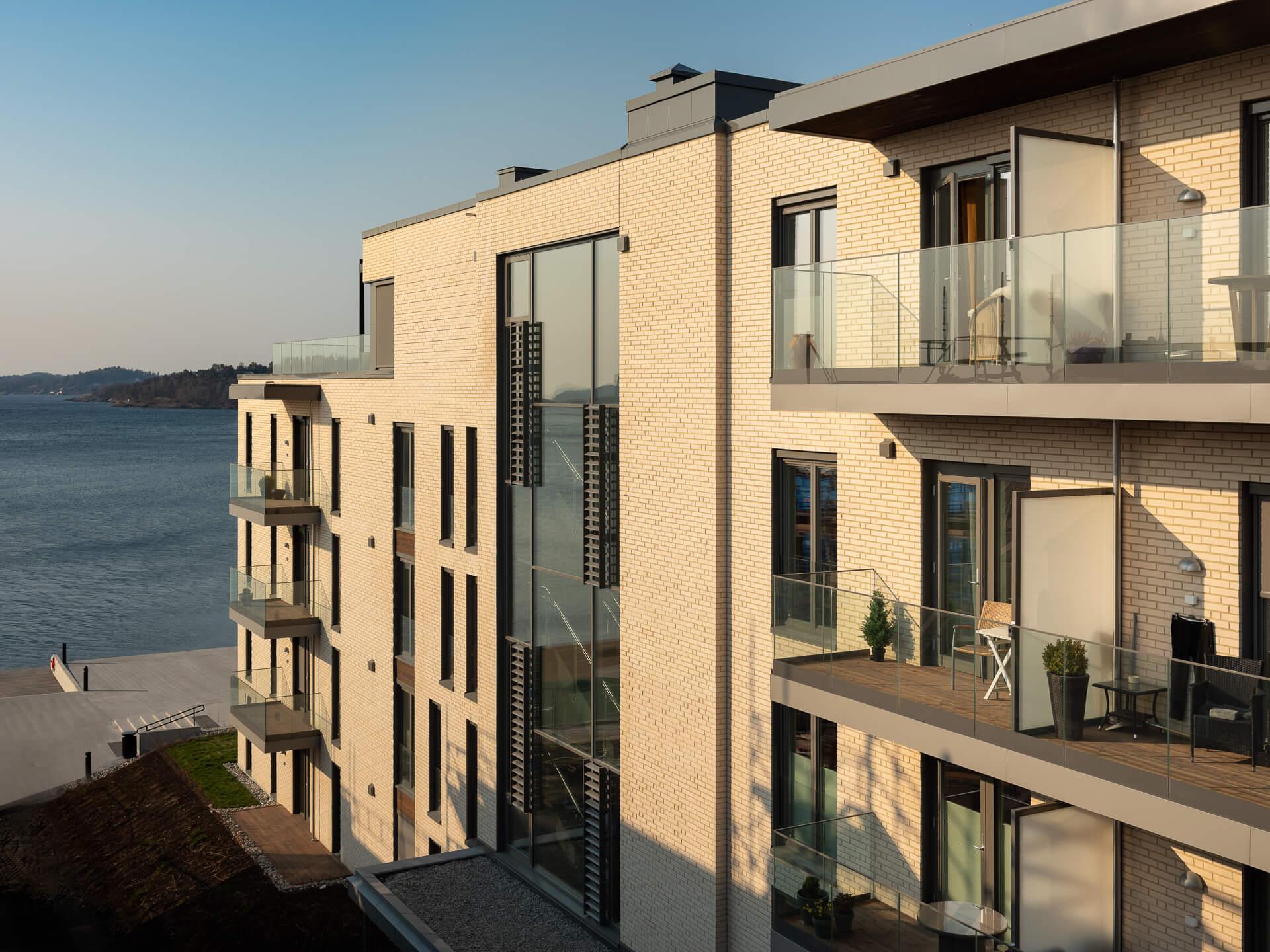 Sunlit apartment blocks with glass balconies by the sea at Sanden